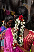 Scented garlands of fresh flowers swaying in women black hair near the Swamimalai temple. 